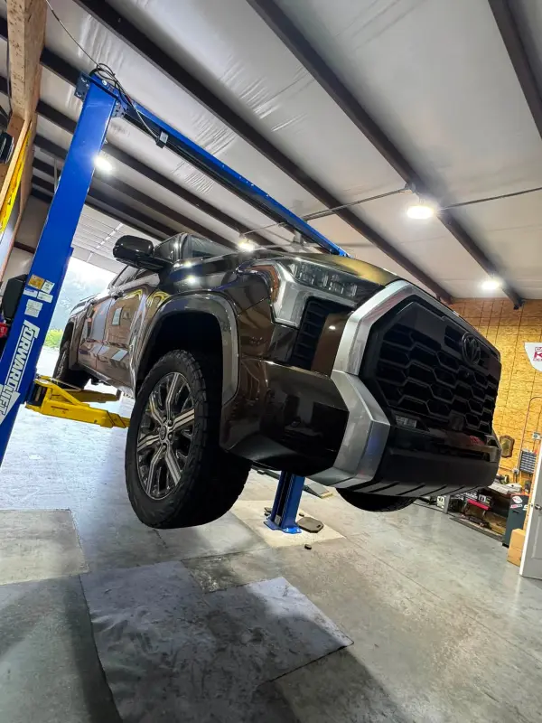 A Toyota Tundra up on the lift in the Blessed Beginnings bay with a new set of tires mounted